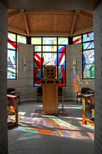 Entrance to octagonal St. Michael Chapel with tabernacle surrounded by stained glass.