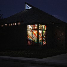 "Creation": a stained glass window of imported mouthblown German glass at night.